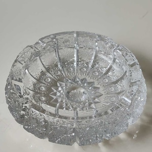 Peut inclure: Un cendrier en verre transparent avec un motif en verre taillé. Le cendrier est rond et a un bol profond.