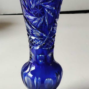 Pode incluir: Um vaso de vidro azul cobalto com um design de vidro cortado. O vaso tem uma boca larga e uma base redonda.