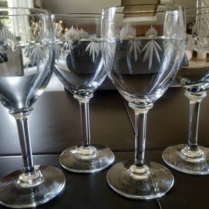 Peut inclure: Quatre verres à vin en verre transparent avec des motifs gravés. Les verres ont une tige haute et fine et un bol rond.