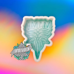 May include: A white silicone mold with the word "AMAM" in raised lettering. The mold is shaped like a heart with a decorative design.