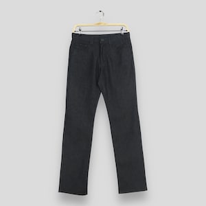 May include: Dark grey denim trousers with a straight leg design, featuring a button and zip closure, and classic five-pocket styling. The trousers are hanging on a gold-coloured hanger.
