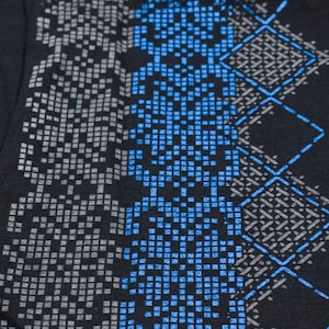May include: Black fabric with a geometric pattern in shades of gray and blue. The pattern is made up of small squares and diamonds.