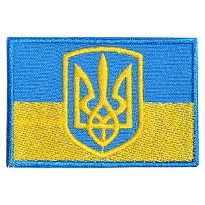 May include: A blue and yellow embroidered patch featuring the Ukrainian coat of arms, a trident, in the center.