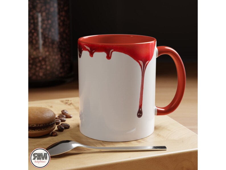 May include: White ceramic mug with a red rim and red dripping paint design. The mug has a handle.