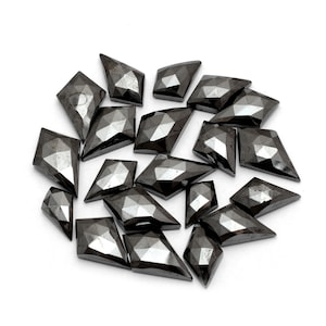 May include: A collection of black diamond shaped gemstones with faceted edges. The stones are arranged in a circular pattern on a white background.
