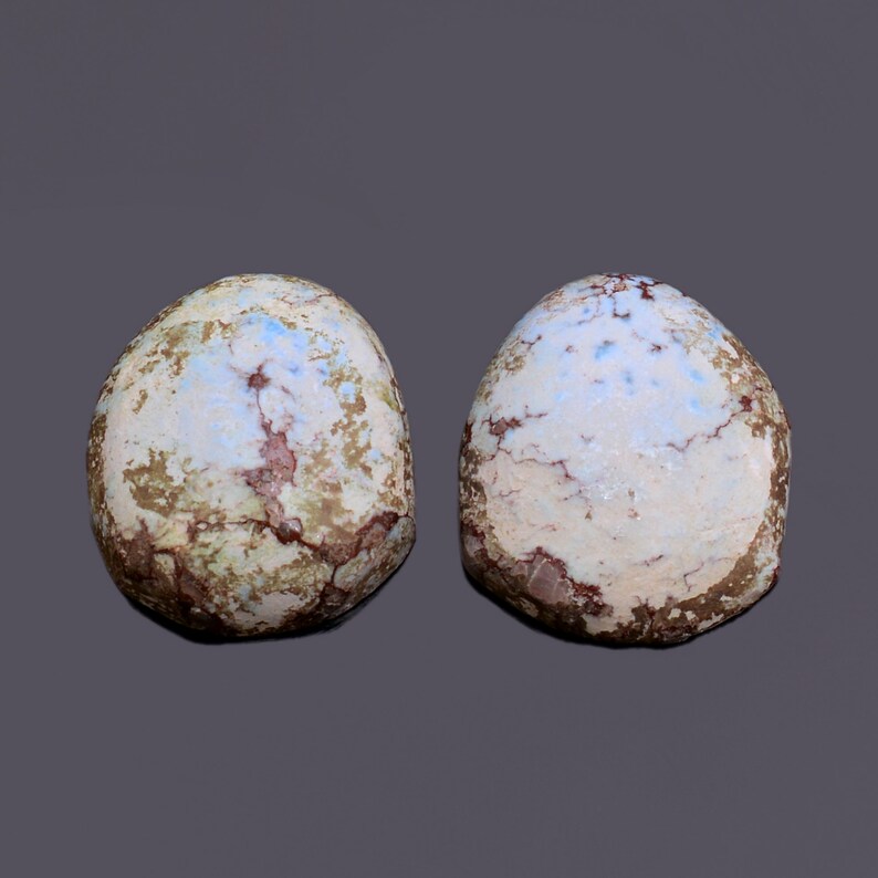 May include: Two round, smooth, light blue, green, and brown stones with a cracked and textured surface.