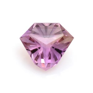 Könnte beinhalten: Ein facettierter Edelstein mit einem komplexen Schliff, der eine Mischung aus rosa und lila Farbtönen zeigt. Das symmetrische Design des Edelsteins weist mehrere Facetten auf, die das Licht reflektieren und einen funkelnden Effekt erzeugen. Der Edelstein ist vor einem weißen Hintergrund platziert.