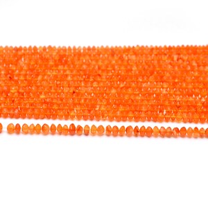 May include: A strand of orange carnelian beads, with a smaller strand of the same beads below it. The beads are faceted and have a smooth, polished finish.