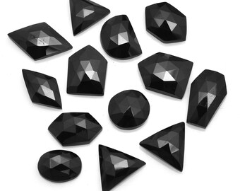 May include: A collection of 12 black gemstone cabochons in various shapes, including round, oval, triangle, and diamond. The gemstones are faceted and have a shiny, polished finish.