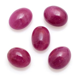 Peut inclure: Cinq pierres précieuses ovales polies d'une teinte rose foncé. Les pierres précieuses sont disposées en demi-cercle sur un fond blanc.