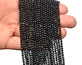 May include: A strand of black faceted gemstone beads. The beads are small and round, and they are strung together on a clear thread.