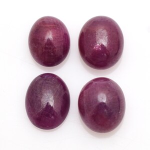 May include: Four oval-shaped, deep red gemstones with a polished finish. The gemstones are arranged in a square pattern on a white background.