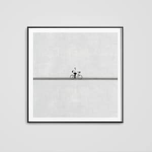 Könnte beinhalten: Ein gerahmter Kunstdruck mit minimalistischem Design. Eine Person fährt mit dem Fahrrad auf einer grauen Linie vor einem strukturierten, hellgrauen Hintergrund. Das Kunstwerk wird in einem schwarzen Rahmen präsentiert und schafft eine klare und moderne Ästhetik.