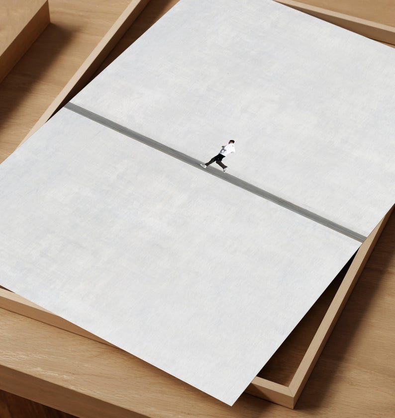 May include: An aerial view of a person running on a gray road, set against a large white background. The image is presented within a wooden tray, creating a minimalist and artistic composition.