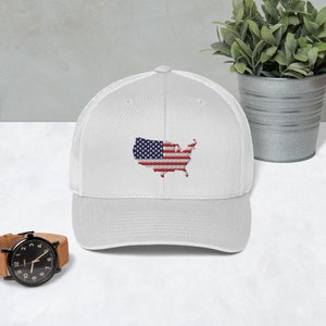 May include: White baseball cap with a mesh back. The front of the cap features an embroidered image of the United States in the shape of the country with the American flag design.