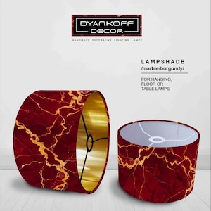 Può includere: Due paralumi con un design marmorizzato bordeaux e interno dorato. Il testo sull'immagine recita "DYANKOFF DECOR" e "LAMPSHADE /marble-burgundy/ FOR HANGING, FLOOR OR TABLE LAMPS."