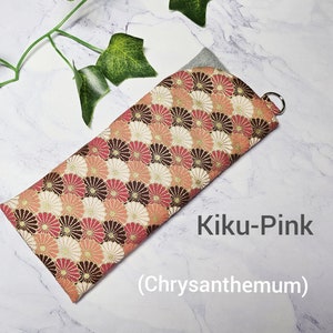 May include: A pink and brown fabric eyeglass case with a chrysanthemum pattern. The case has a silver zipper pull and the text "Kiku-Pink (Chrysanthemum)" is printed on the white background.