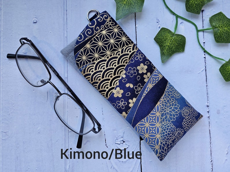 May include: A blue and gold fabric glasses case with a Japanese-inspired pattern. The case has a zipper closure and is made of a soft, durable fabric.