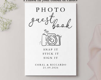 May include: A white rectangular sign featuring the black text PHOTO guest book, a line drawing of a camera with a heart, and the text SNAP IT STICK IT SIGN IT. Below is the text CORAL & RICCARDO 21.09.2026 and six colored circles.
