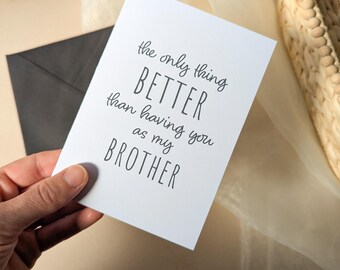 May include: A white greeting card with black text that reads, the only thing BETTER than having you as my BROTHER. The card is rectangular with a smooth finish and features a mix of cursive and block lettering for the message printed on the front.