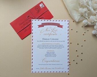May include: A white Father Christmas Nice List certificate with red and white striped borders, gold stars, and text addressed to Damon Celestini. Beside it lies a red envelope tied with red and white twine, featuring a stamp and handwritten address.