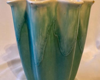 May include: A light blue ceramic vase with a scalloped rim and five openings. The vase has a gradient of light blue to white.