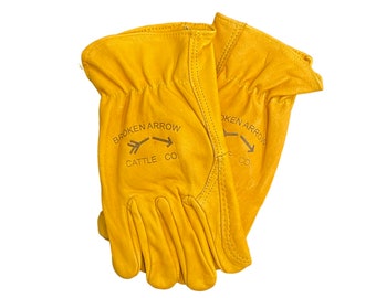 May include: A pair of yellow leather work gloves with the text "BROKEN ARROW CATTLE CO." printed on the back of the left glove.
