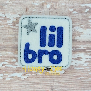 May include: A white felt square patch with a blue embroidered star and the text "lil bro" in blue embroidery.