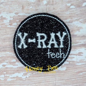 May include: Black and white embroidered patch with the text "X-RAY teeth" on a black glitter background.