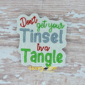 May include: White felt Christmas ornament with green and red embroidery. The ornament reads "Don't get your Tinsel in a Tangle".