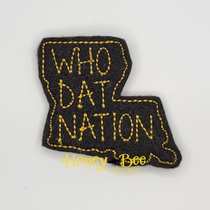 May include: Black felt patch in the shape of the state of Louisiana with yellow stitching. The words "WHO DAT NATION" are stitched in yellow on the patch.