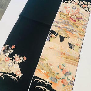 Könnte beinhalten: Zwei dekorative japanische Obi-Gürtel. Einer ist schwarz mit Blumen- und Blattmustern in Rosa, Pfirsich und Creme. Der andere zeigt eine Landschaft mit Bergen, Gebäuden und Blumen in ähnlichen Farben.