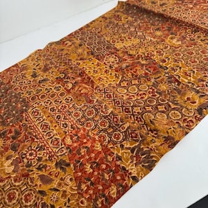 May include: A rectangular textile with a patchwork design. The fabric features a mix of warm colors, including shades of brown, orange, and yellow. The patterns include floral and geometric motifs, creating a vintage or bohemian aesthetic.