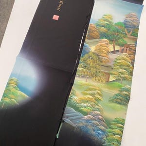 Könnte beinhalten: Eine japanische Bildrolle in Schwarz und Grün, die eine Landschaft mit Bäumen und einem Gebäude darstellt. Die Rolle ist teilweise entrollt und zeigt eine Szene eines Gartens mit einem Weg, der zu einem Gebäude führt. Die Rolle ist in japanischen Schriftzeichen signiert.