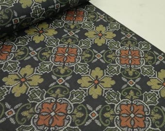 May include: A roll of patterned fabric featuring a repeating floral design. The pattern includes orange, olive green, and white floral motifs on a dark background. The fabric is likely used for sewing or crafting projects.