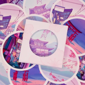 Op de afbeelding: Een set van 10 ronde stickers met verschillende Japanse geïnspireerde scènes. De stickers zijn gedrukt op wit papier met een glanzende afwerking. De scènes omvatten een traditioneel Japans gebouw, een rode torii-poort, een straatbeeld en een bergketen. De stickers zijn perfect om een ​​toets van Japanse cultuur toe te voegen aan je laptop, waterfles of planner.