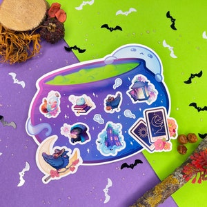 Puede incluir: Una pegatina grande con un caldero morado con líquido verde y varias ilustraciones temáticas de Halloween. Incluye un cuervo en una luna creciente, cartas del tarot, fantasmas y una casa encantada. El fondo es morado y verde.