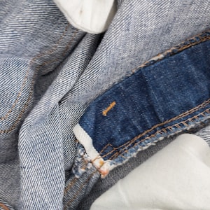Peut inclure: Gros plan sur un tissu en jean bleu avec un panneau bleu fonc&eacute; contrastant et une doublure en tissu blanc. Le denim a un motif de tissage diagonal subtil.