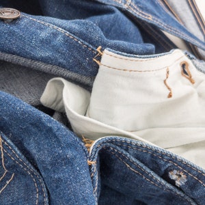 Peut inclure: Gros plan sur une veste en jean bleu avec une doublure blanche. La veste est d&eacute;boutonn&eacute;e et la doublure est visible. Le denim est us&eacute; et d&eacute;lav&eacute;.