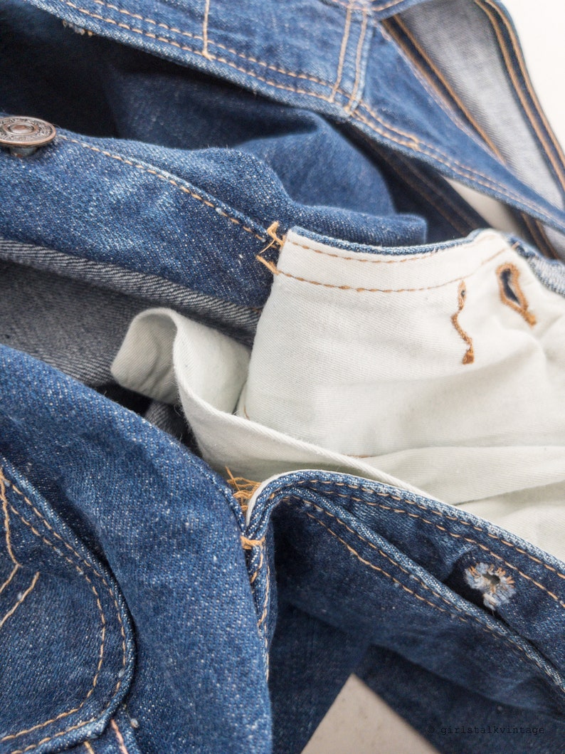 Peut inclure: Gros plan sur une veste en jean bleu avec une doublure blanche. La veste est d&eacute;boutonn&eacute;e et la doublure est visible. Le denim est us&eacute; et d&eacute;lav&eacute;.