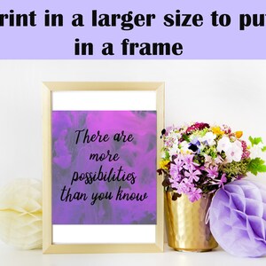 May include: A framed print with a purple watercolor background and the text "There are more possibilities than you know". The print is sitting on a white surface with a bouquet of flowers and a purple honeycomb ball.