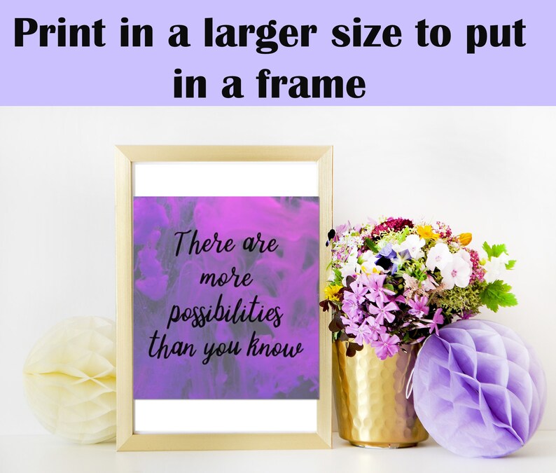 May include: A framed print with a purple watercolor background and the text "There are more possibilities than you know". The print is sitting on a white surface with a bouquet of flowers and a purple honeycomb ball.