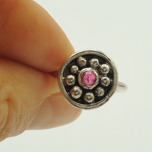 May include: A silver ring with a pink gemstone surrounded by small silver beads.