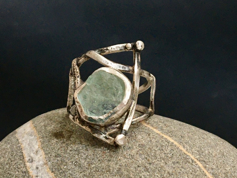 May include: A silver ring with a large, light blue aquamarine stone set in a cage-like design.