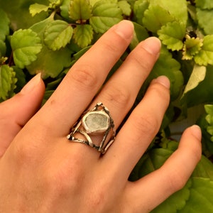 May include: A silver ring with a geometric design featuring a light green gemstone.