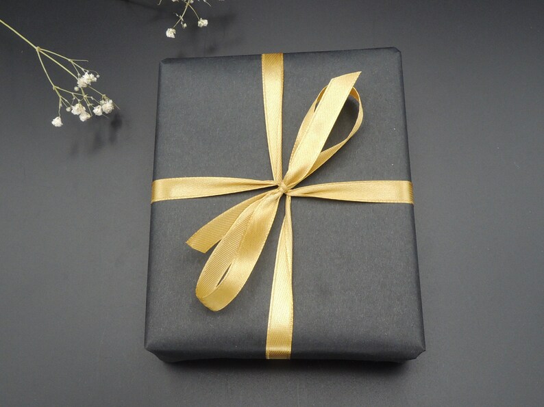 May include: A black gift box with a gold ribbon tied in a bow.