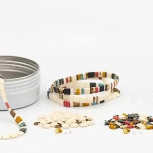 May include: A set of colorful tile bracelets in a white tin with beads and string for making bracelets.