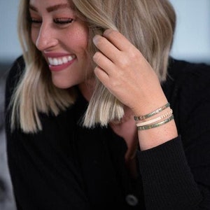 a woman smiles as she adjusts her bracelet