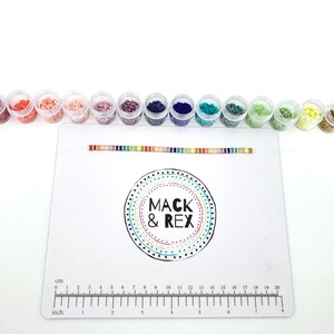 image of multiple colored beads in different plastic of beads, a bracelet, and the wipeable bead mat on a white background. 








Wipeable Bead Mat with Built-in Measuring Tape | Non-Slip Jewelry Making Tool | Perfect Beading Mat for DIY Projects