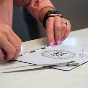 image of a person measuring the length of a bracelet with the in-built measuring tape of the wipeable bead mat. 






Wipeable Bead Mat with Built-in Measuring Tape | Non-Slip Jewelry Making Tool | Perfect Beading Mat for DIY Projects